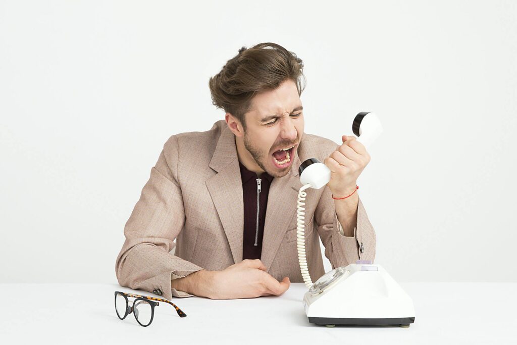 Geërgerde zzp'er schreeuwt in vintage telefoonhoorn, illustratie bij verbod op ongevraagde verkooptelefoontjes per 1 juli 2026